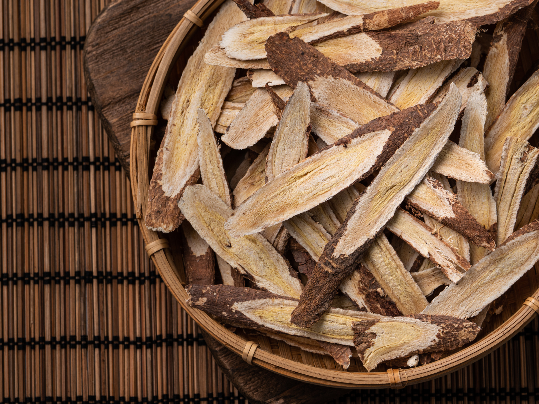 Dried astragalus root slices in a wooden bowl representing herbal immune support for pets