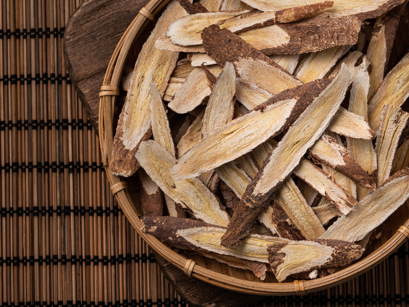 Dried astragalus root slices in a wooden bowl representing herbal immune support for pets