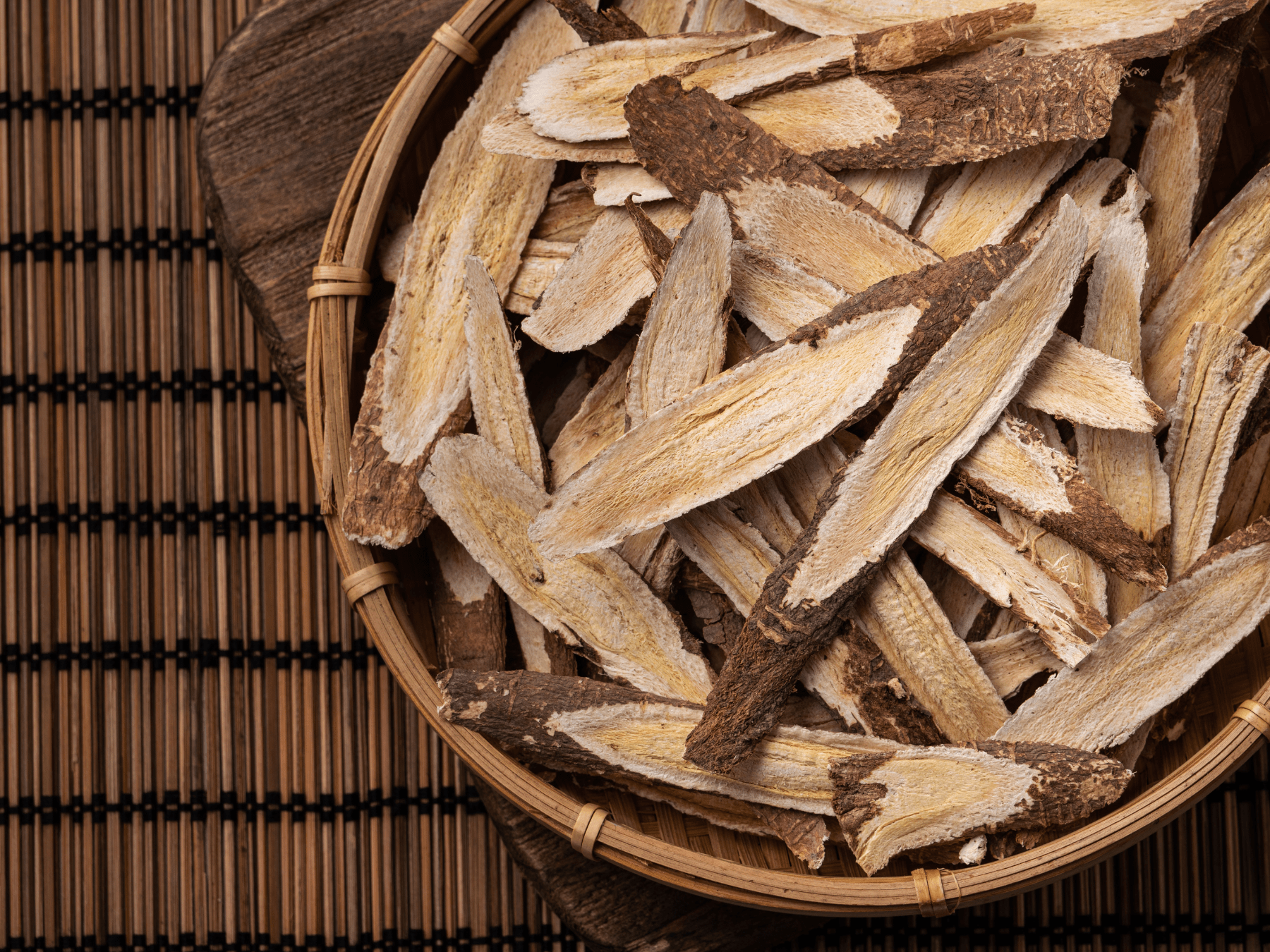 Dried astragalus root slices in a wooden bowl representing herbal immune support for pets
