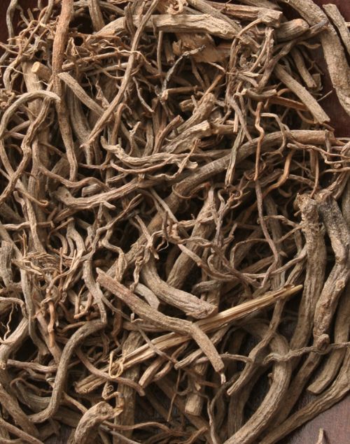 Dried, tangled brown valerian root pieces with a rough, fibrous texture filling the frame.